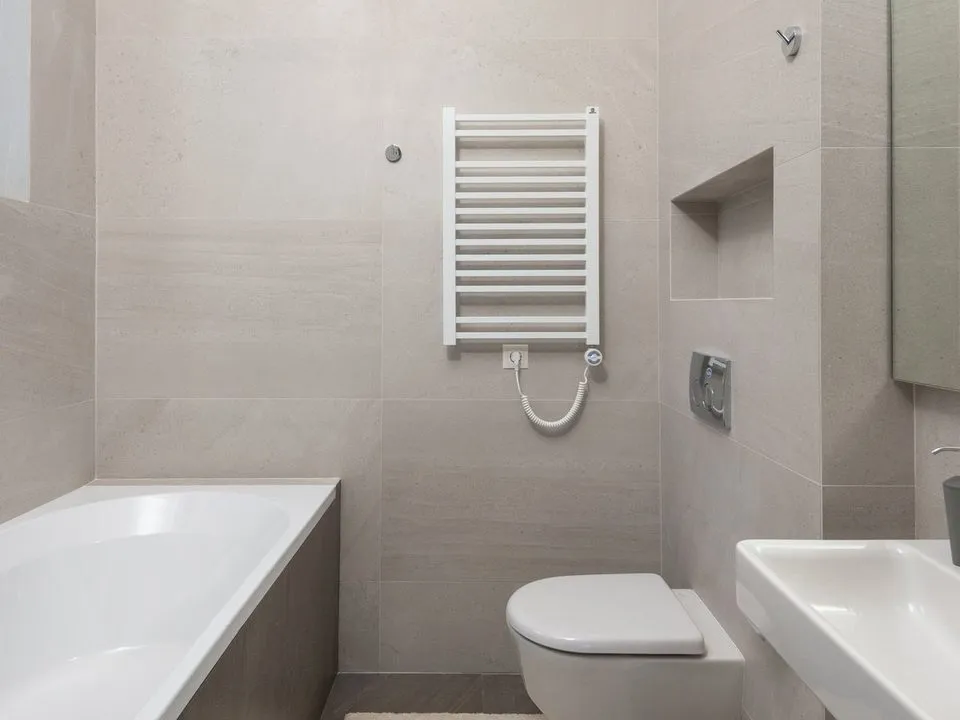 Saniertes Badezimmer mit großformatigen Fliesen, Badewanne und Hänge-WC