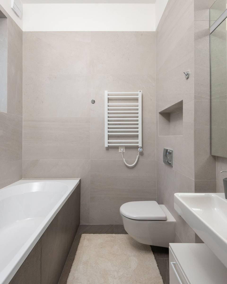 Saniertes Badezimmer mit großformatigen Fliesen, Badewanne und Hänge-WC