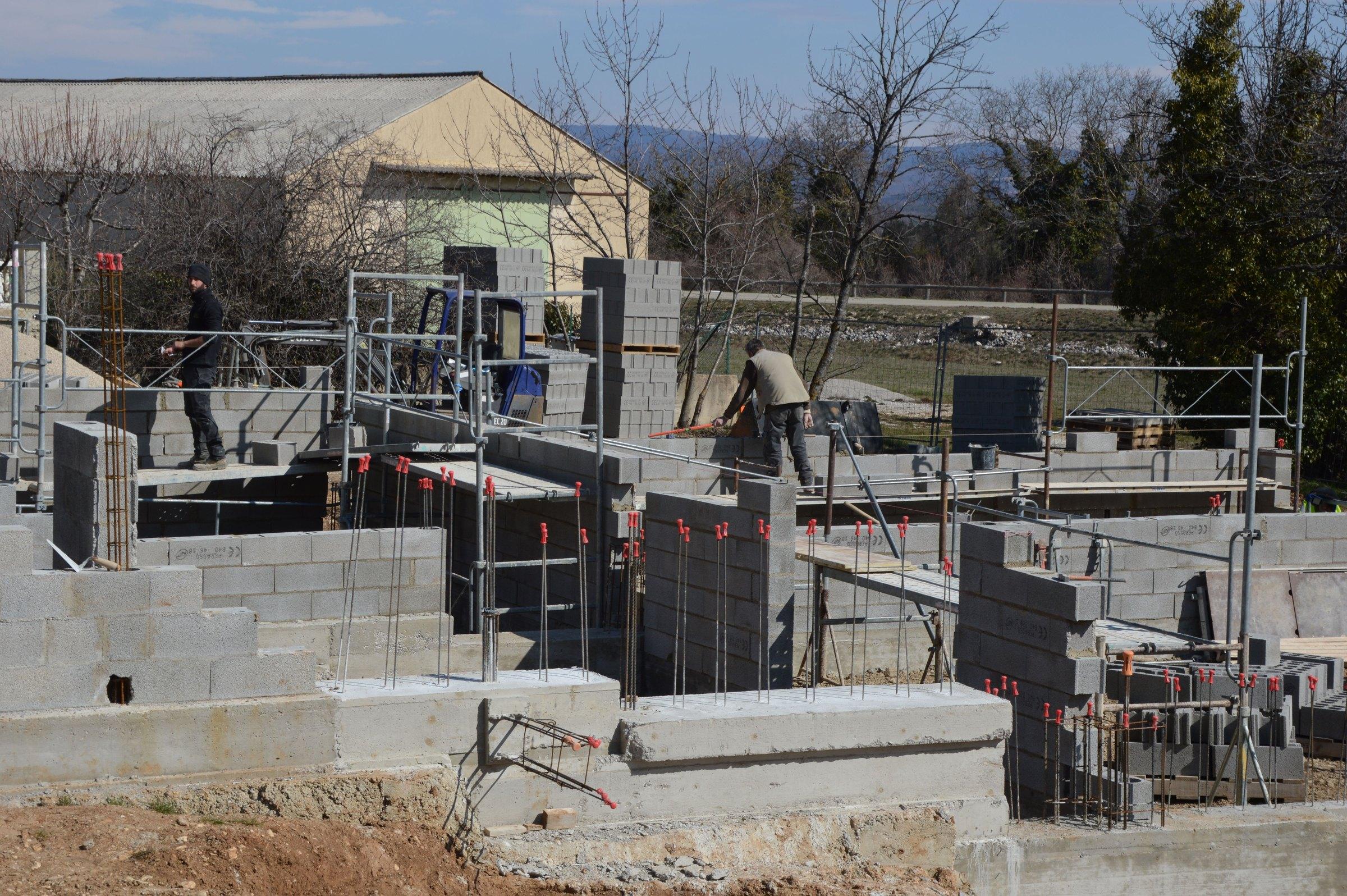 Baustelle mit neu gemauerten Wänden, Gerüst und Handwerkern