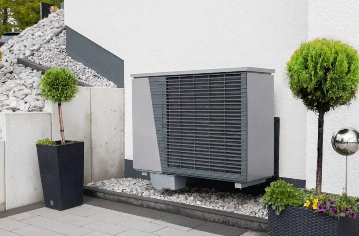 Luft-Wasser-Wärmepumpe an der Außenwand eines modernisierten Einfamilienhauses